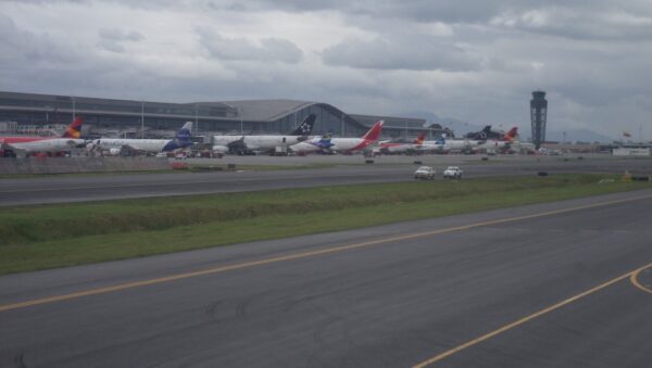Aviones de varias aerolíneas en la plataforma del Aeropuerto Internacional El Dorado de Bogotá con la terminal y la torre de control al fondo