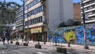 Carrera Séptima peatonal en el centro de Bogotá con peatones, árboles, edificios y un gran mural de colores