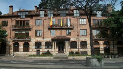 Fachada de ladrillo y piedra del Hotel Casa Medina sobre la carrera Séptima de Bogotá, con balcones, banderas y árboles al frente