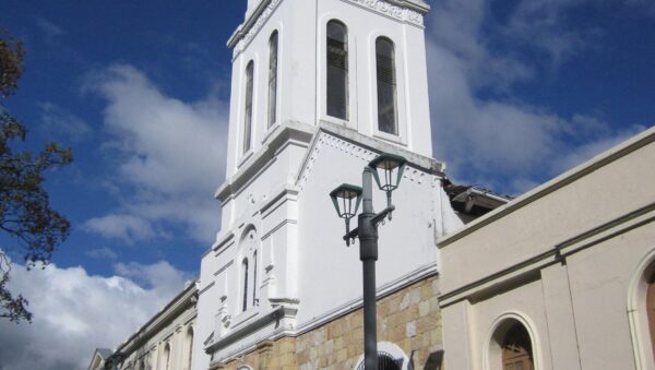 Torre campanario blanca de la Iglesia de Santa Bárbara de Usaquén en Bogotá bajo un cielo azul