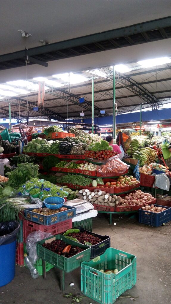 Plaza de Paloquemao en Bogotá: guía, horarios y qué probar 1 Puestos llenos de frutas y verduras de colores bajo la cubierta de la Plaza de Mercado Paloquemao en Bogotá