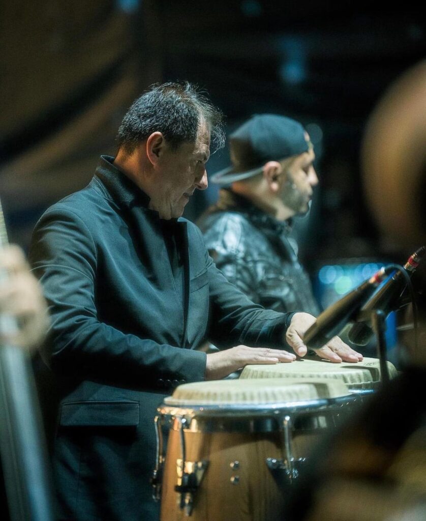 Percusionista tocando congas con chaqueta oscura durante un concierto de Salsa al Parque en Bogotá, con otro músico al fondo