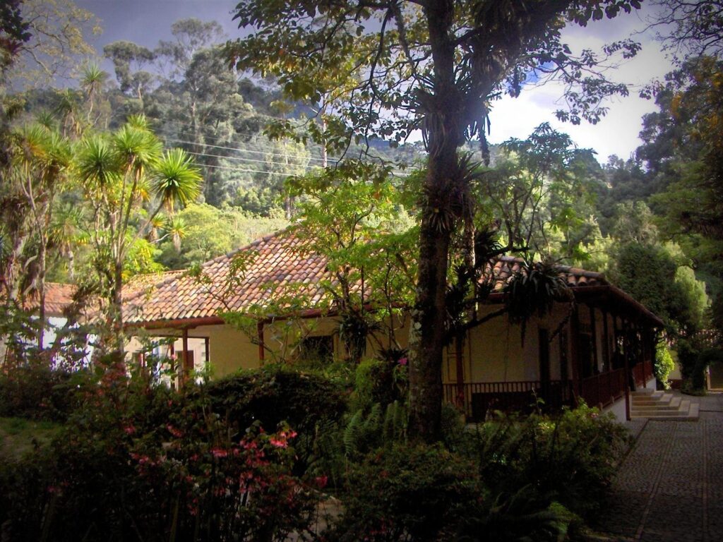 Quinta de Bolívar en Bogotá: horarios, tarifas y qué ver 1 Casa colonial de la Quinta de Bolívar en Bogotá con techo de teja, rodeada de árboles y jardines al pie del cerro
