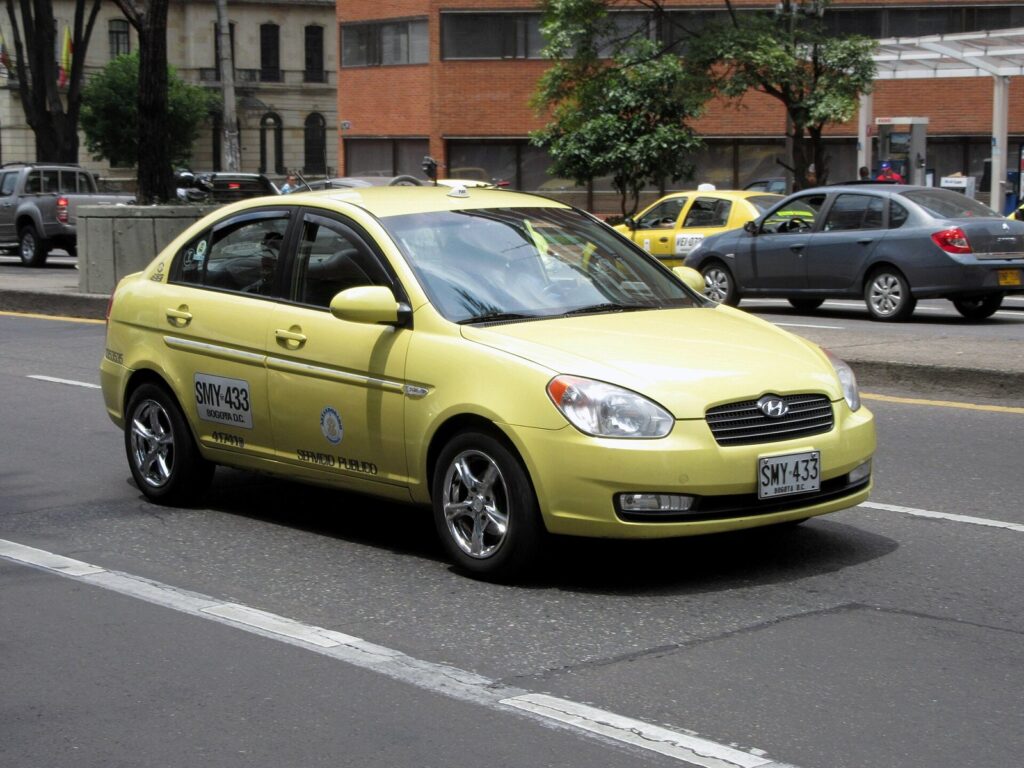 Taxi amarillo circulando por una avenida de Bogotá